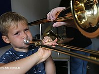Ein Kind probiert einen Ton auf der Posaune zu spielen.