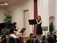 Eine Querflötenspielerin wird von einer Gitarristin im Konzert begleitet.