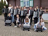 Gruppenfoto der Mitglieder des Akkordeonorchesters mit ihren Instrumenten vor dem Jagdhaus der Jugendherberge Gorenzen.