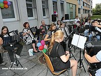Akkordeonschüler musizieren im Orchester vor dem Musikschulgebäude.