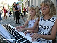 Musikschülerinnen spielen zu zweit auf einem E-Piano.