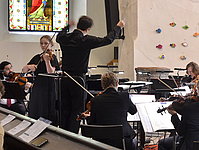 Auftritt einer Violinschülerin mit dem Orchester unter der Leitung des Dirigenten.