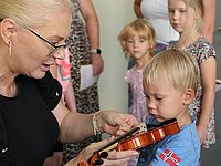 Eine Lehrerin erklärt einem Kind, wie man die Geige richtig hält.