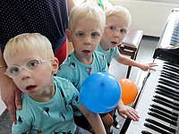 Am Klavier probieren Drillinge und sind vom Klang fasziniert.