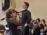 Sängerin mit Mikrofon beim gemeinsamen Aufritt mit dem Orchester.