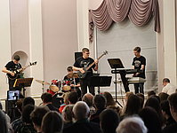 Vier Musiker einer Jugendband musizieren im Konzert.