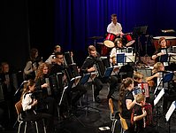 Zweite Teilaufnahme des Orchesters mit großen und leinen Musikern. Im Hintergrund der Schlagzeuger.