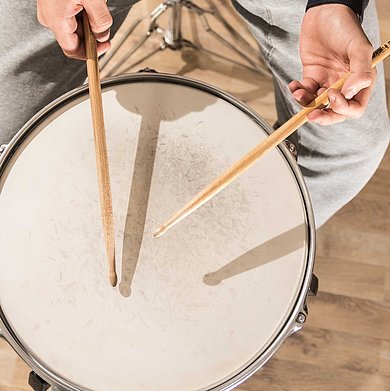 Spielende Hände mit Drumsticks auf einer Snaredrum