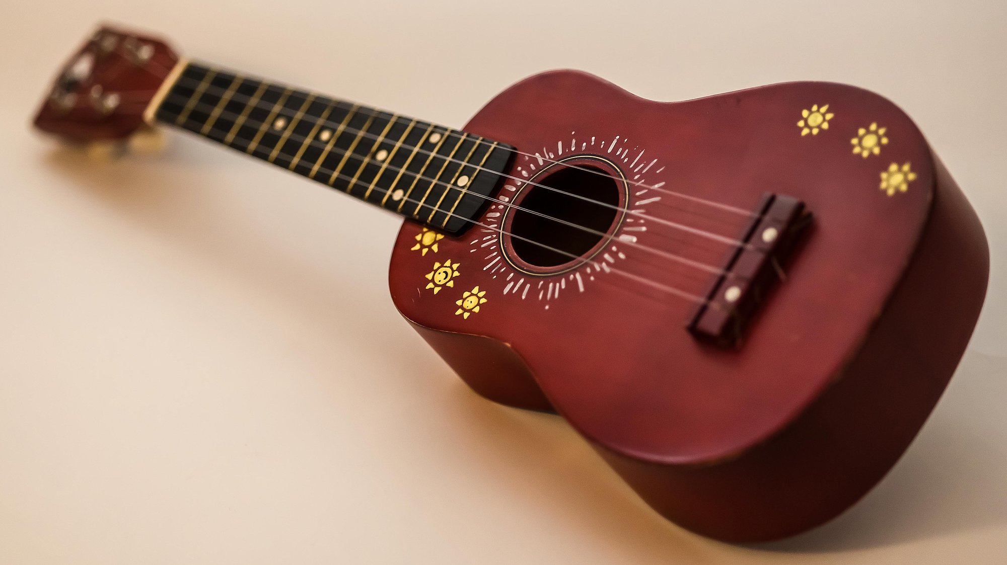 Ukulele aus rotbrunem Holz mit handgemalten Verzierungen auf dem Korpus
